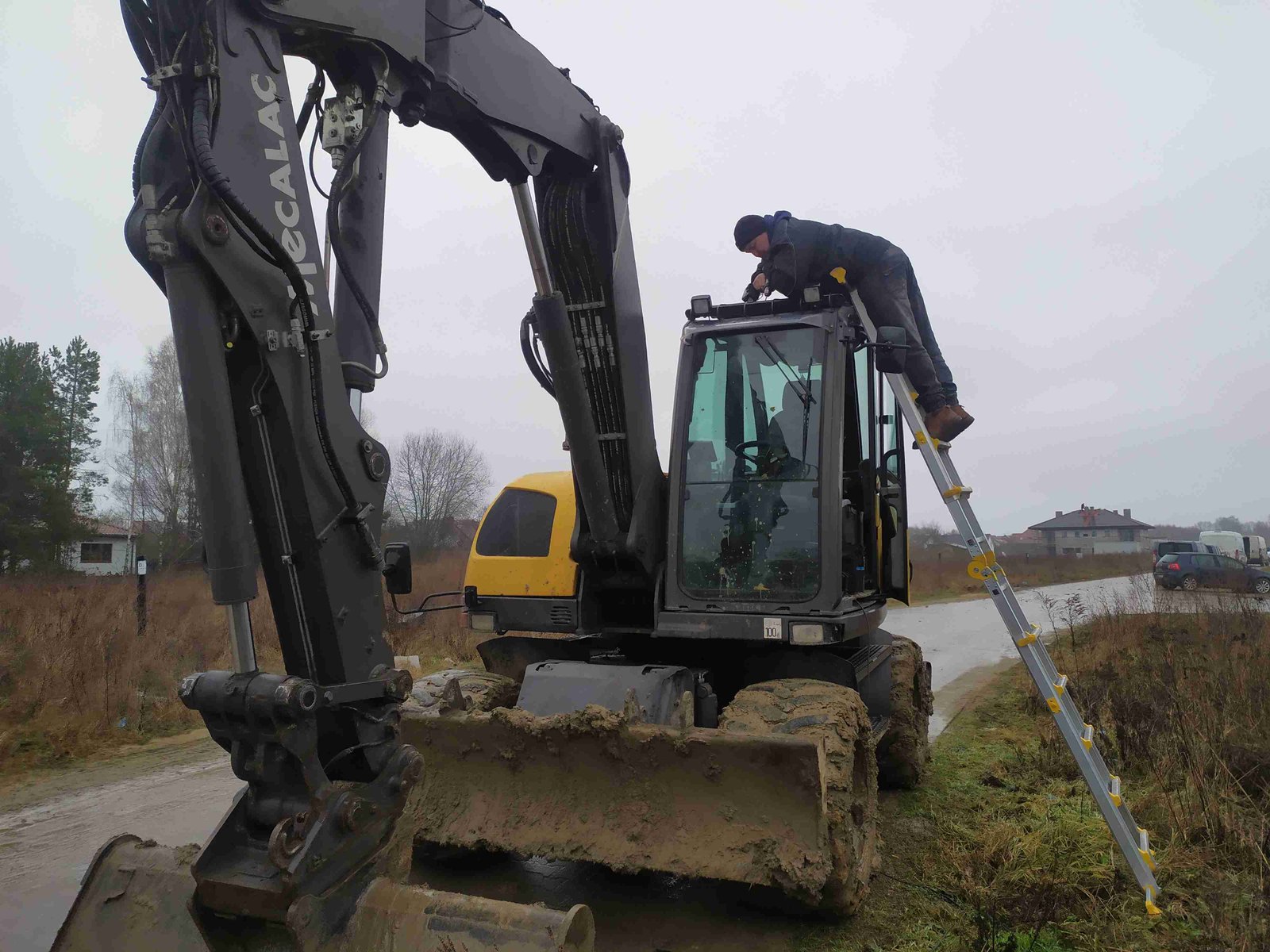Koparka KOMATSU z zamontowanym systemem monitoringu na drabinie, w terenie budowy
