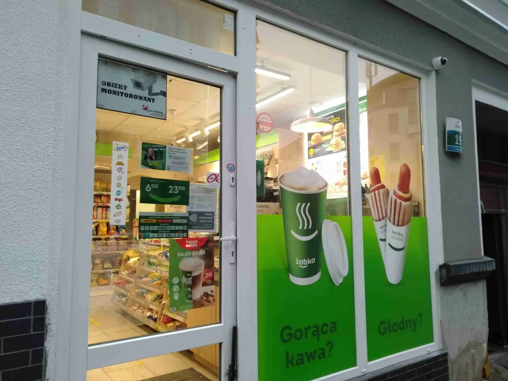 Wejście do sklepu Żabka z tablicą Obiekt monitorowany